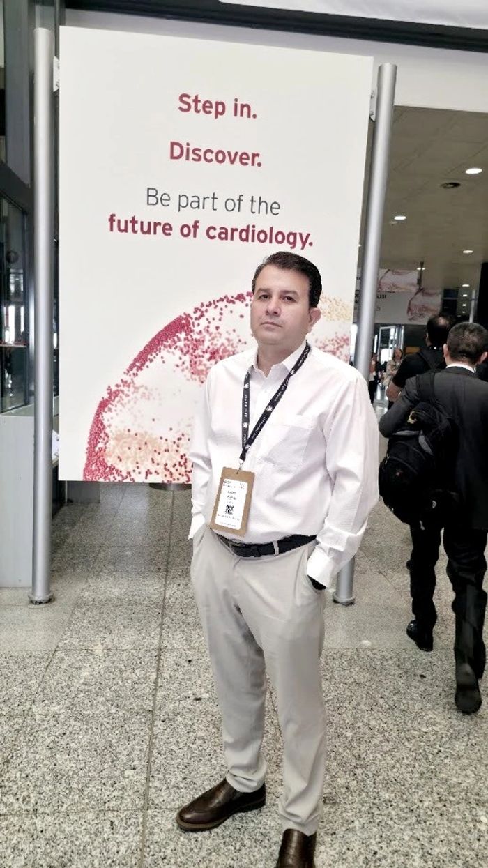 Man in white shirt at a cardiology event with a sign about future cardiology.