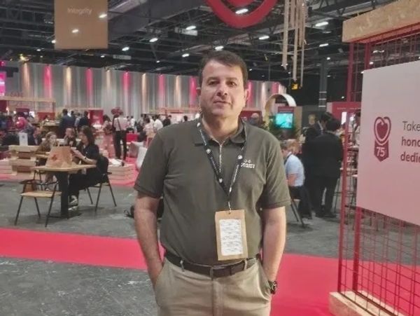 Man standing confidently on a red carpet at a professional event or conference.