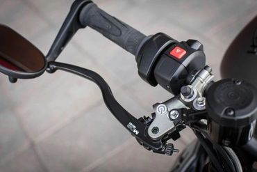 Close-up of a motorcycle handlebar with clutch lever and control switches.