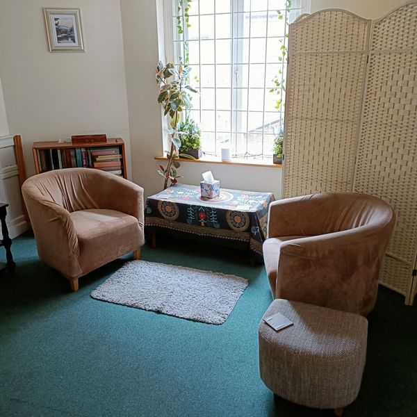 Cozy sitting area with two armchairs, a small table, and a room divider by the window.