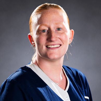 Smiling woman with red hair in navy and white outfit.