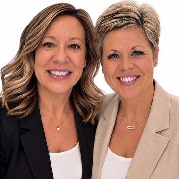 Two smiling women in business attire posing closely.