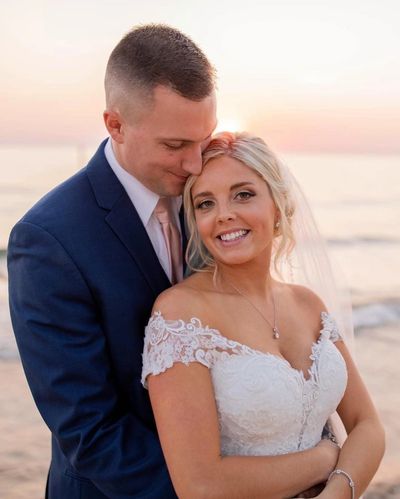 Bride on the beach with her new husband in her wedding gown in a sandbar spray tan. 