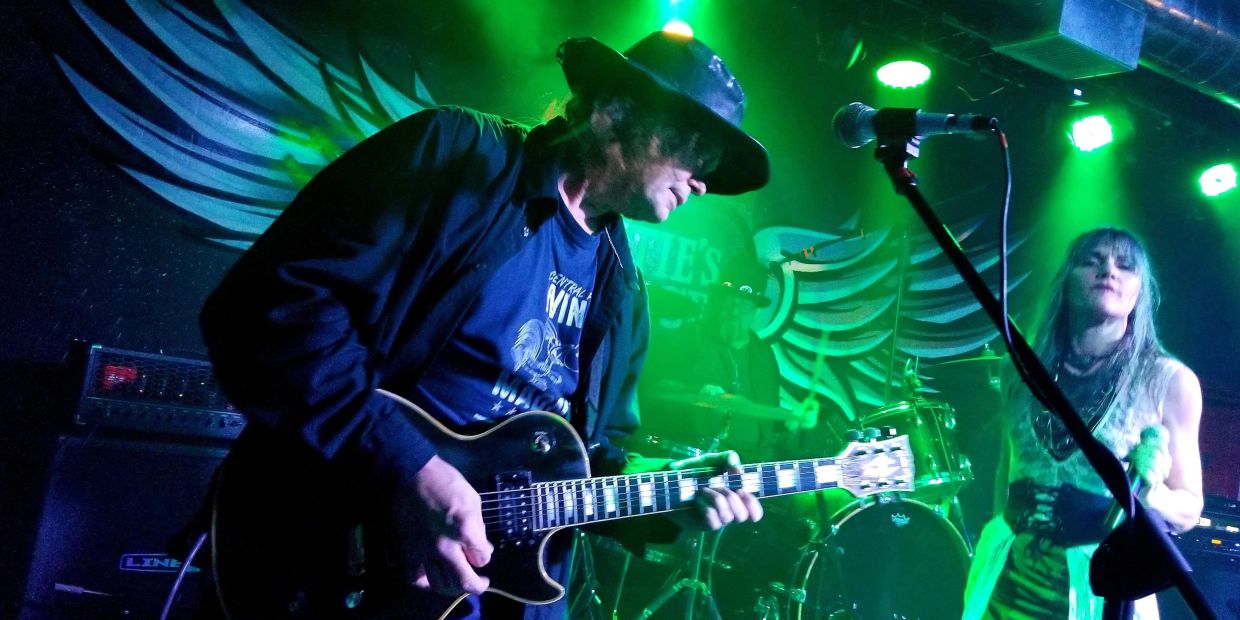 Band performing live on stage with green lighting.