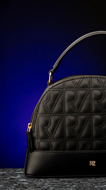Black designer handbag with embossed pattern and gold accents.