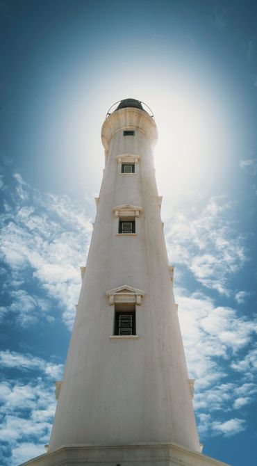 Tall white lighthouse under a bright sky.