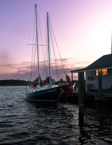 Sailboat docked near a pier at sunset.
