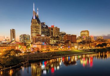 City skyline at twilight with colorful reflections on water.
