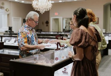 People shopping at a jewelry store counter.
