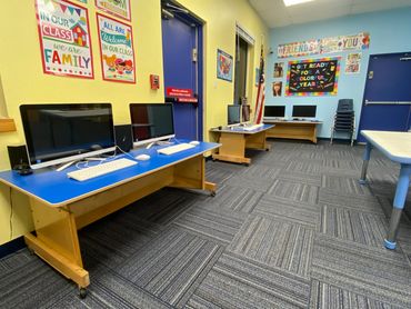 Classroom with computer desks and educational posters.