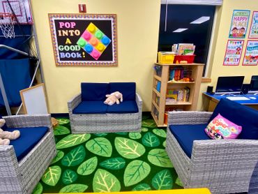 Cozy reading corner in a classroom with comfy chairs and a colorful carpet.