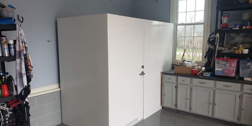Large white storage unit with a door in a garage workspace.