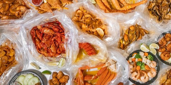 A large spread of assorted seafood dishes with lemon and sauces. cajun crab legs crawfish doordash uber eats delivery rockstar shrimp