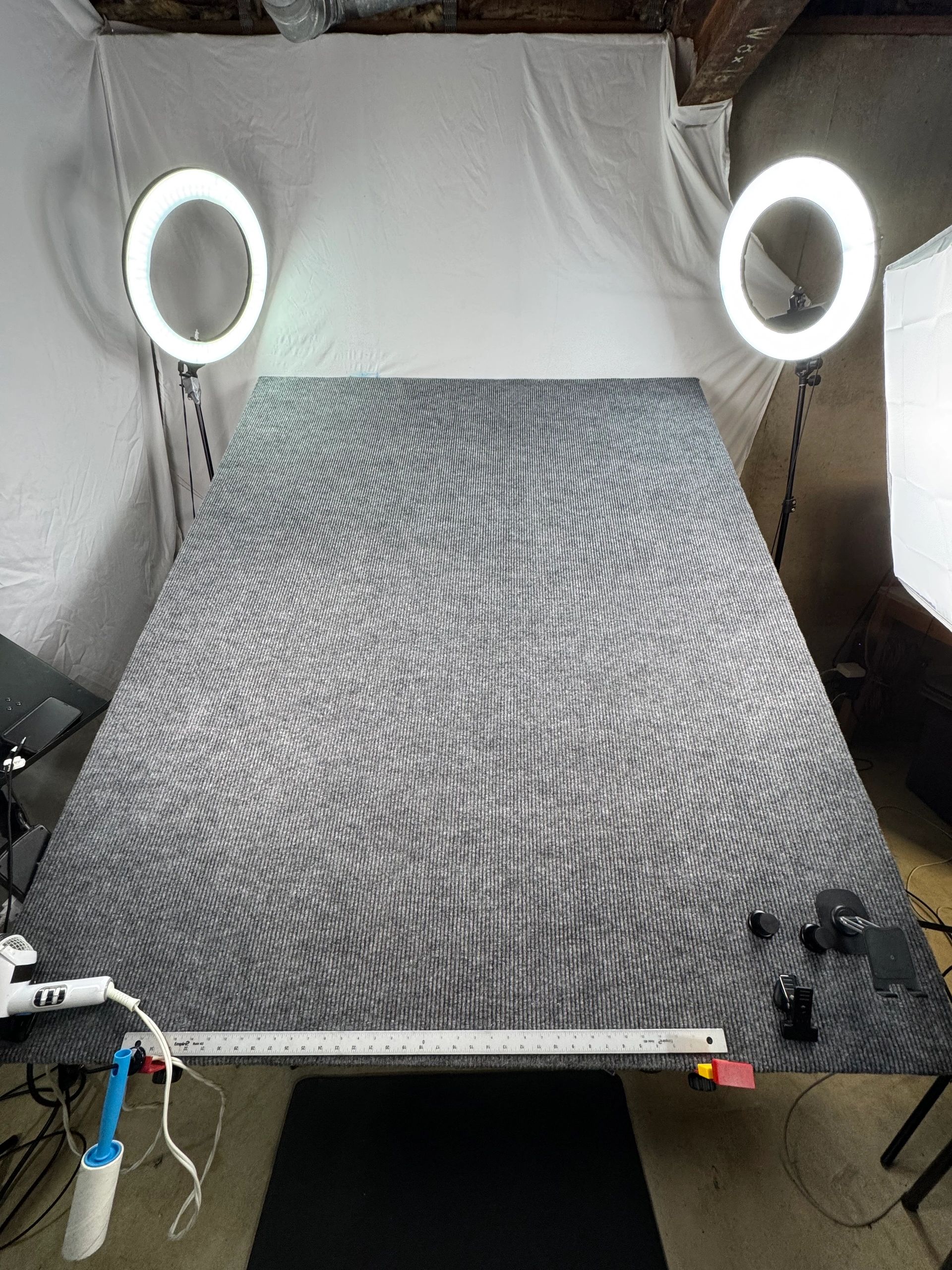 Photography setup with ring lights and a textured grey backdrop.