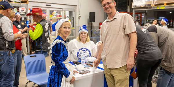 People enjoying a festive event indoors, two in holiday attire at a table.