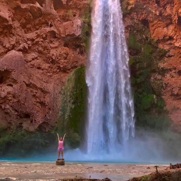 Woman standing in front of Mooney Falls waterfall in Havasu Arizona 