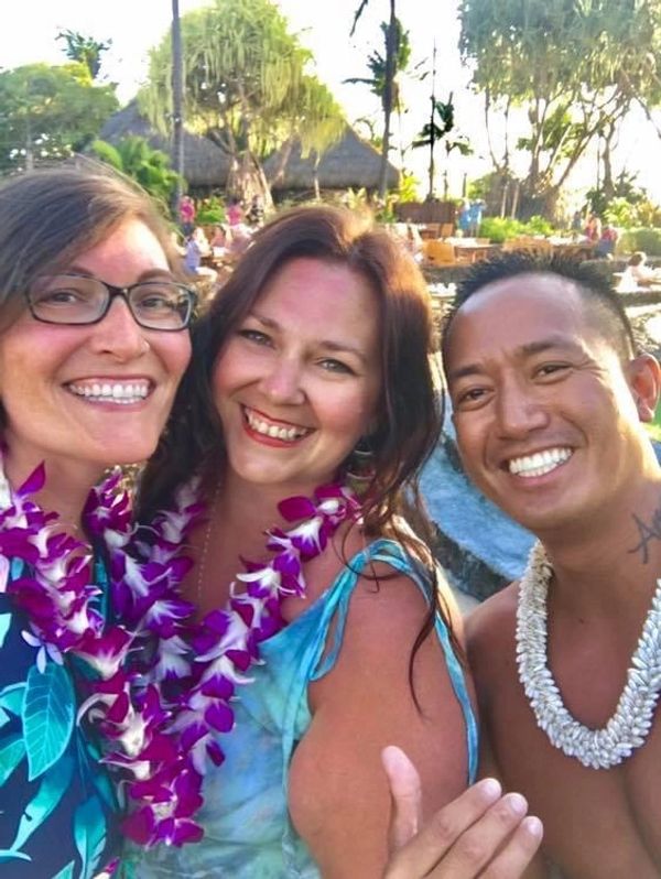 Two white women and a Hawaiian man wearing leis at a luau in Lahaina Maui Hawaii