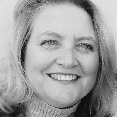 Black and white close-up of a smiling woman with light hair.