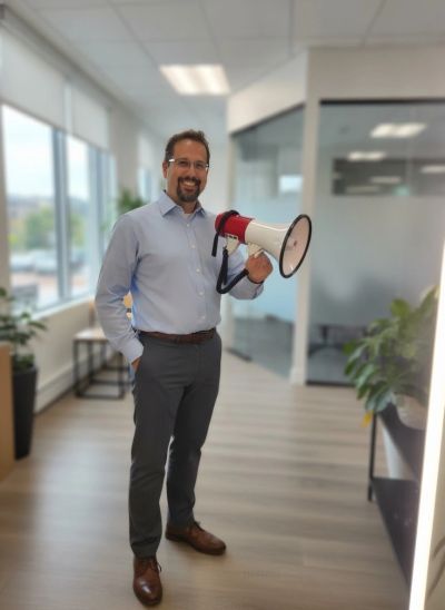 Smiling man in office holding a megaphone.