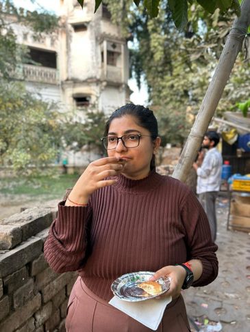 Woman enjoying tea and snacks outdoors near a rustic building.