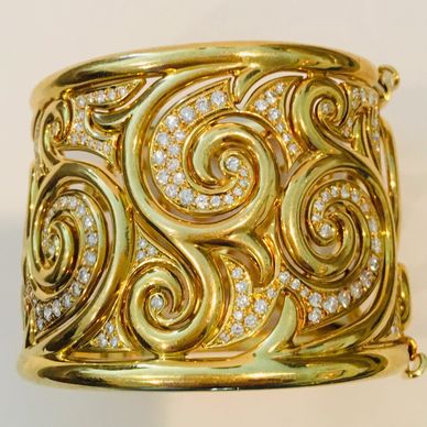 Beautifully made 18K gold cuff bracelet.  with scrolled design inset with diamonds.