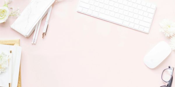 Elegant pink workspace with keyboard, mouse, glasses, and floral accents.