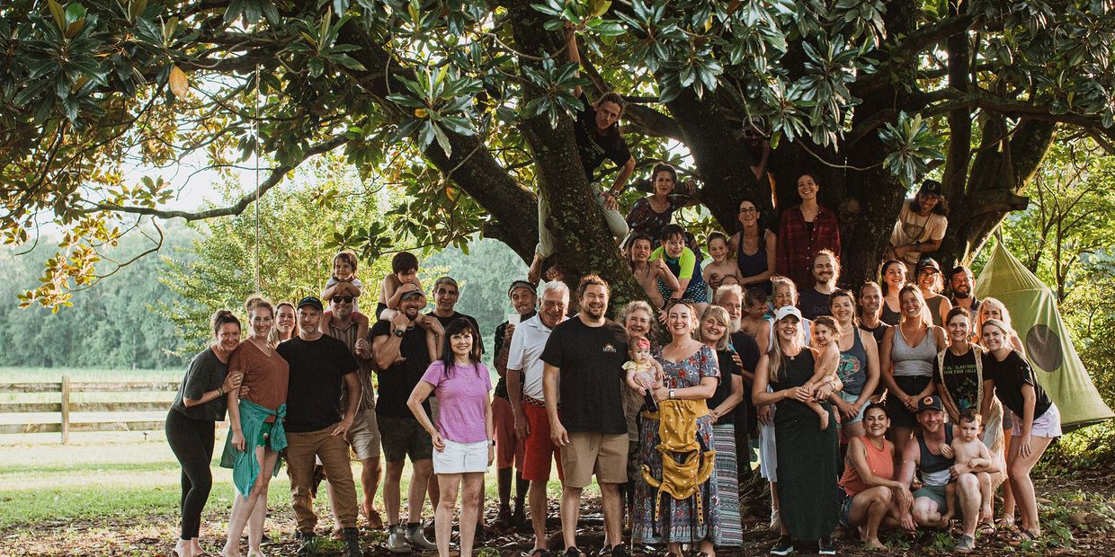 Large family gathering outdoors under a tree.