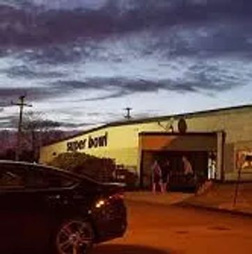 Exterior of a bowling alley named Super Bowl during dusk.