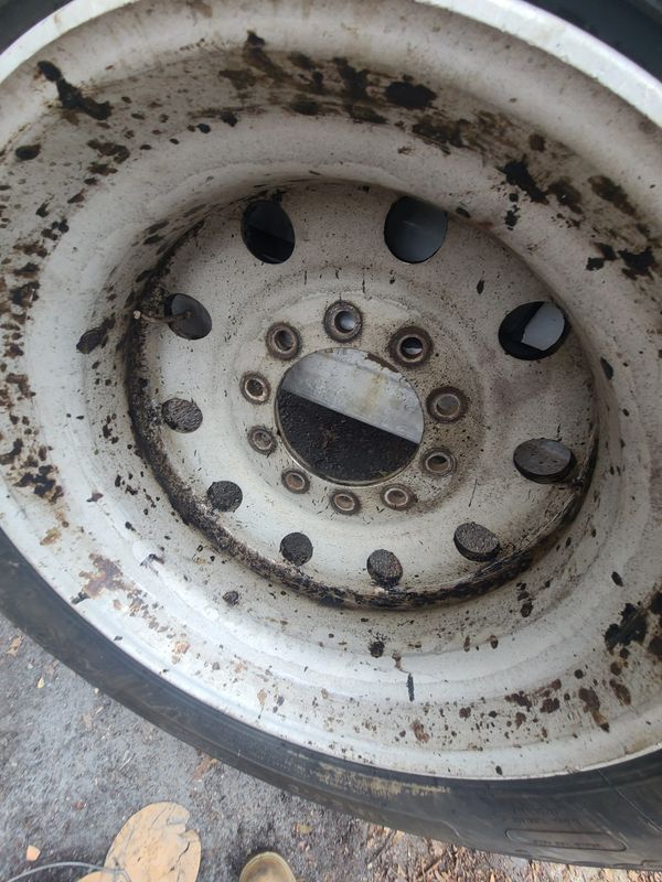 Close-up of a rusty and dirty white metal wheel rim.