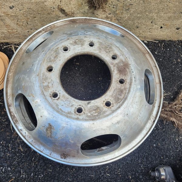 A dirty, used metal wheel rim with multiple bolt holes and vents.