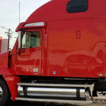 Red semi-truck cab parked outdoors on a clear day.