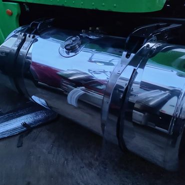 Shiny chrome fuel tank attached to a green vehicle with reflective surface.