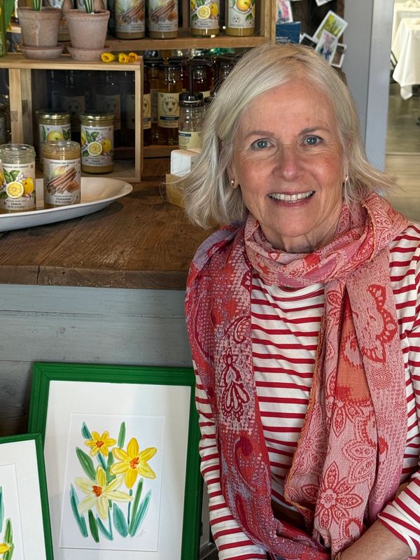 Smiling woman in striped shirt and floral scarf indoors.