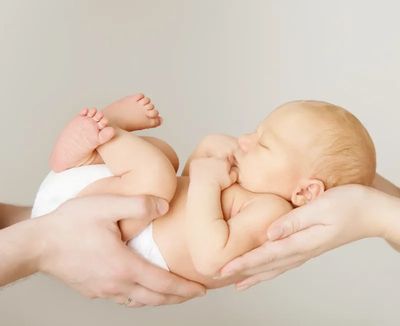 Newborn baby peacefully sleeping in adult hands.