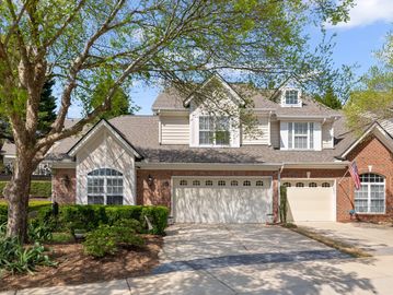 Two-story suburban house with a three-car garage and greenery.