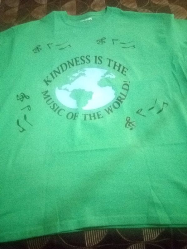 Green T-shirt with the message: Kindness is the music of the world.