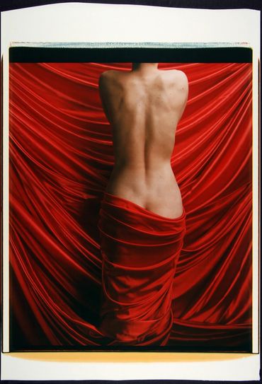 The backside of a topless woman and a red fabric 