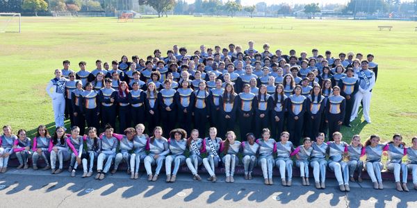 Large marching band group photo outdoors in uniform.