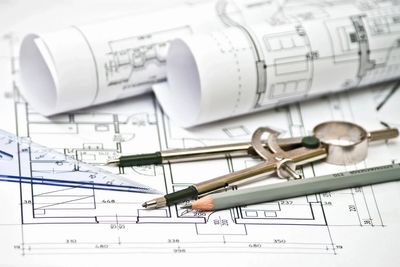 Architectural blueprints with drafting tools and pencils on a desk.