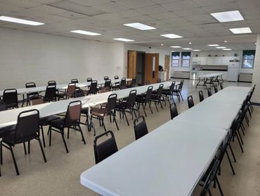A large, empty meeting room with rows of tables and chairs.