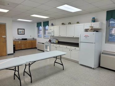 A clean, spacious break room with white cabinets and folding tables.