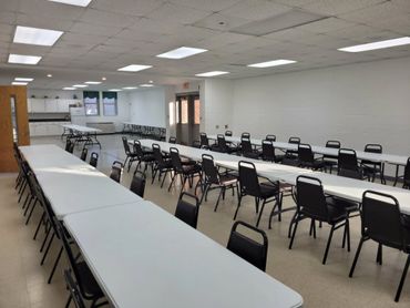 Empty large room with rows of tables and chairs arranged for an event.