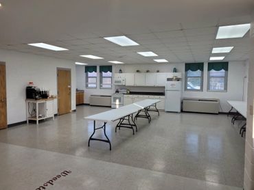 A clean, spacious room with folding tables and bright overhead lights.