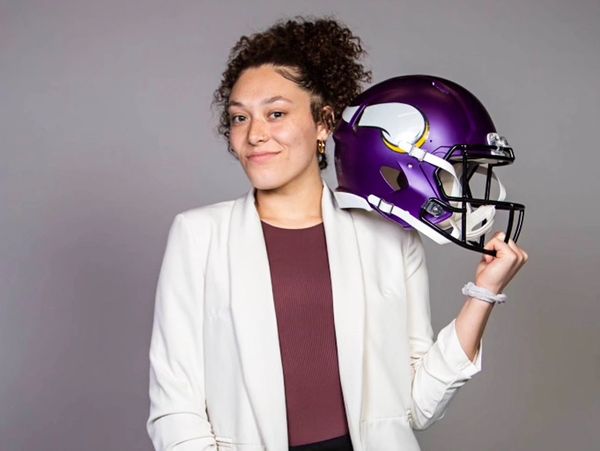 Woman holding a football helmet and smiling.
