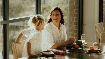A woman and a girl smiling and talking at a dining table.