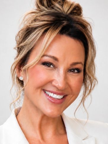 Smiling woman with light brown hair styled in an updo and diamond earrings.