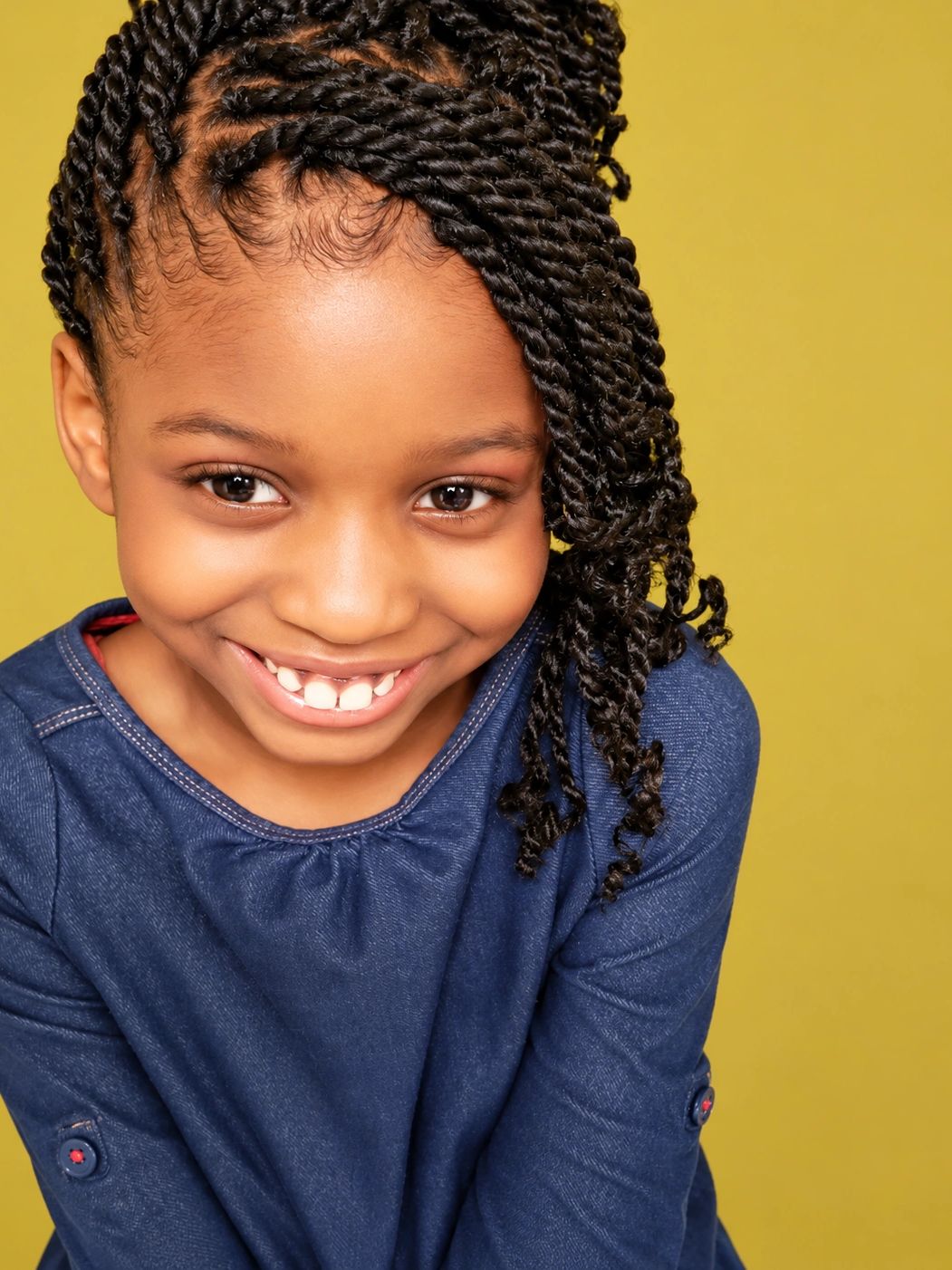 Smiling girl with braided hair in blue shirt.