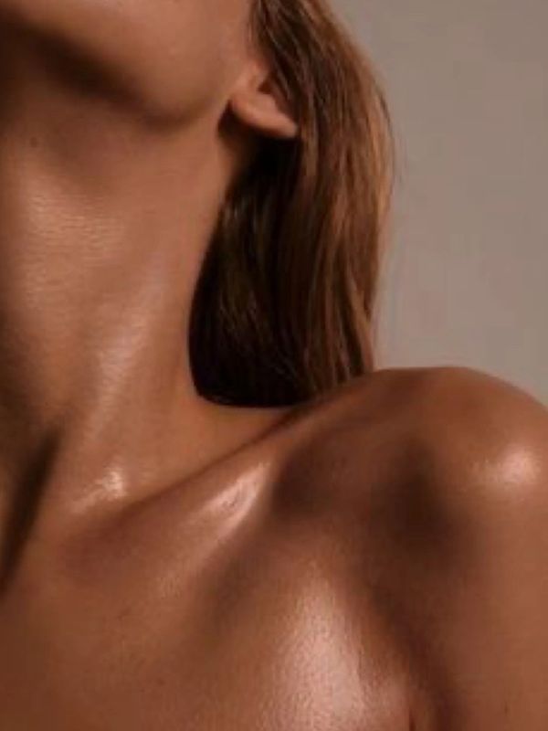 Close-up of a woman's neck and shoulder with glowing skin.