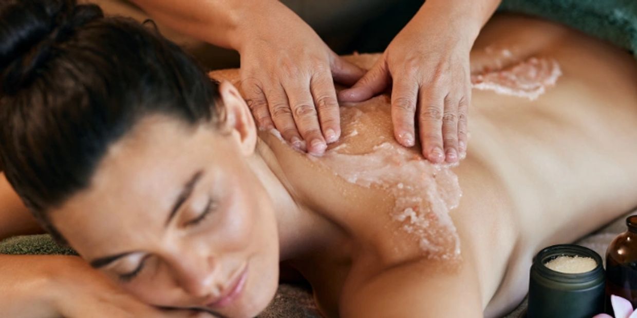 Woman enjoying a relaxing exfoliating back massage at a spa.