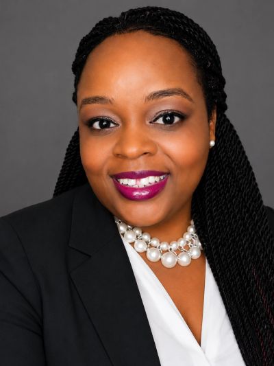 Professional woman with braided hair and pearl necklace.